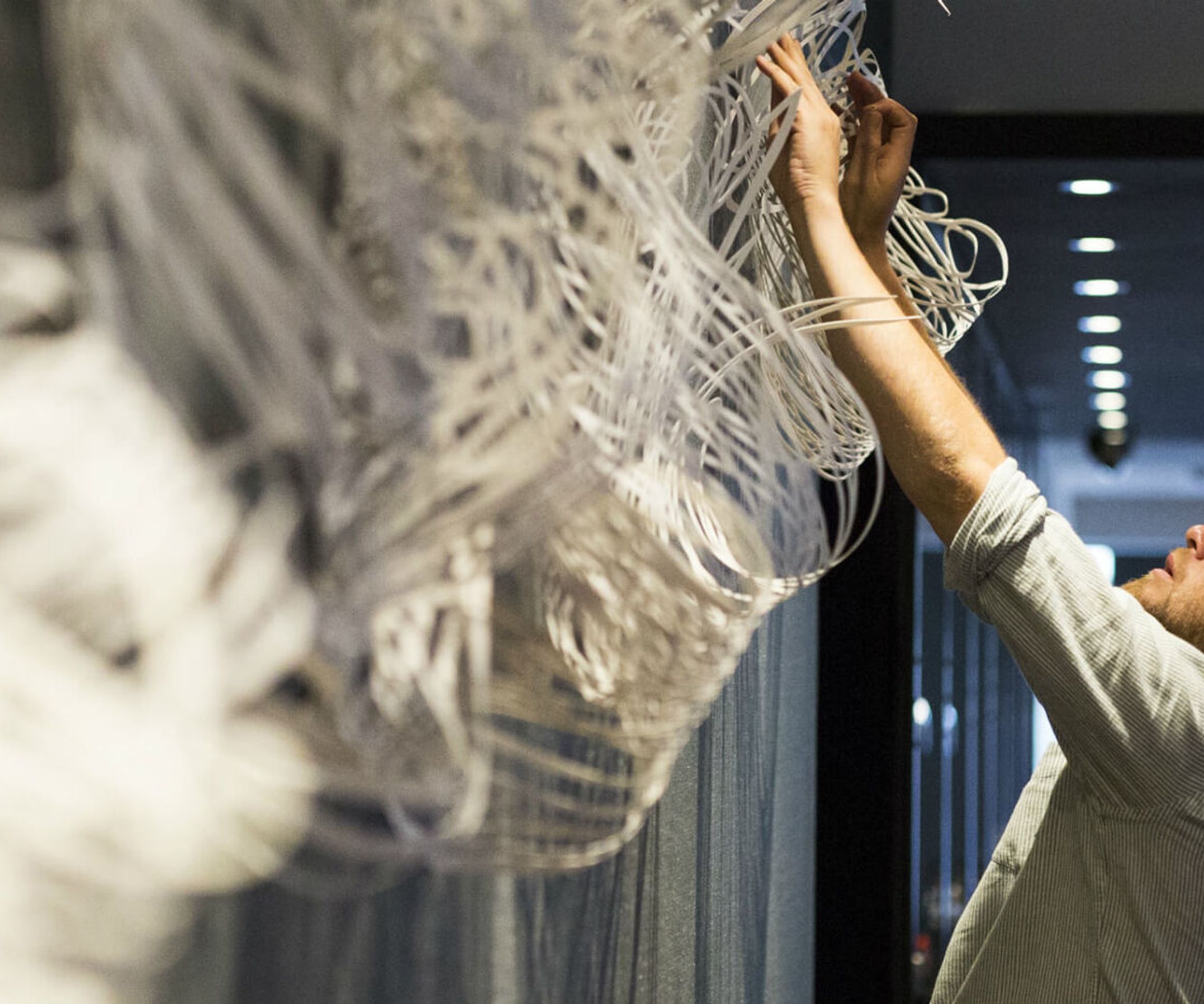 Mann hängt Kunst aus Baumwolle im Motel One Hotel auf