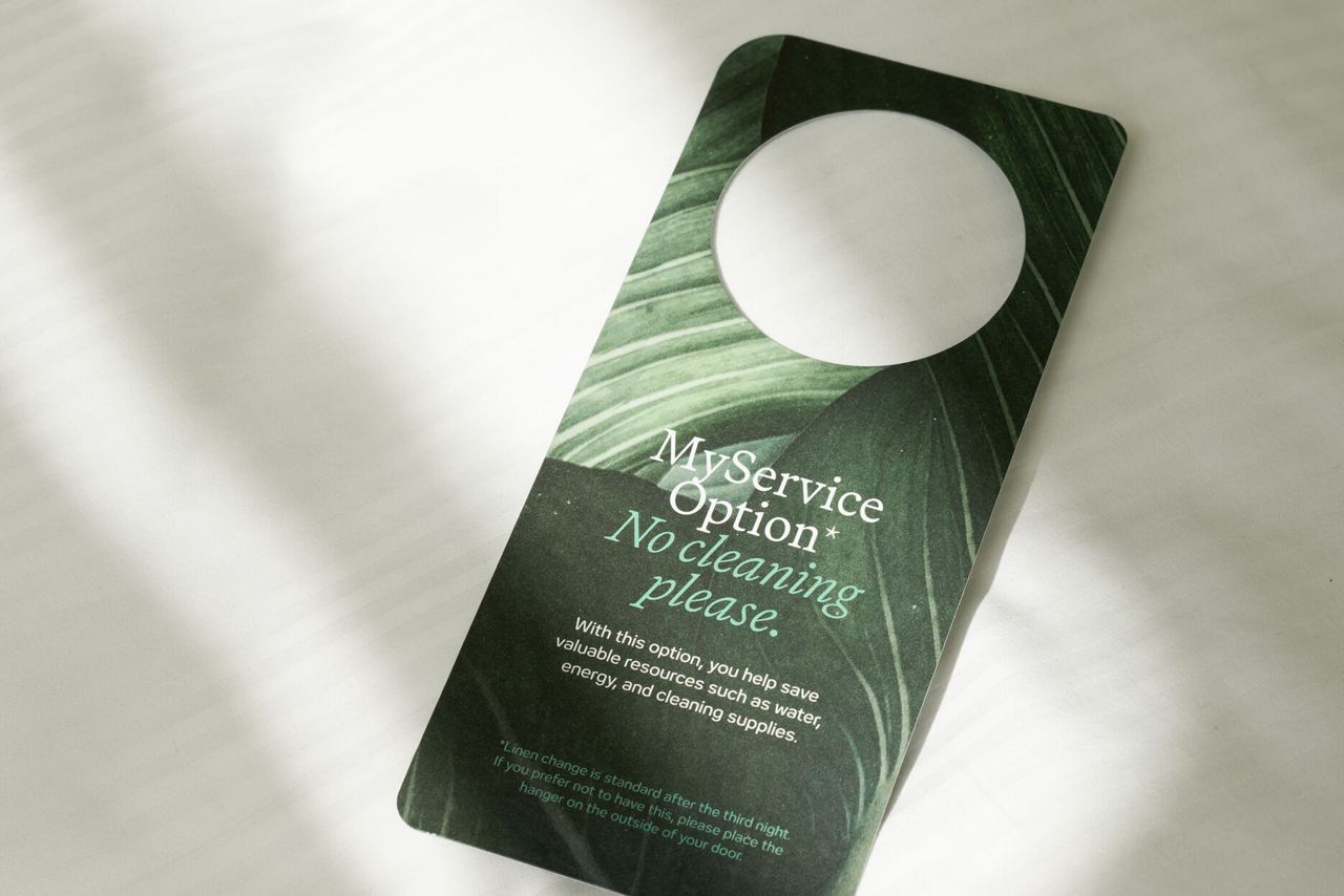 Türanhänger auf weißer Bettwäsche mit der Aufschrift „My service option – No cleaning please“, der anzeigt, dass keine Zimmerreinigung gewünscht ist.