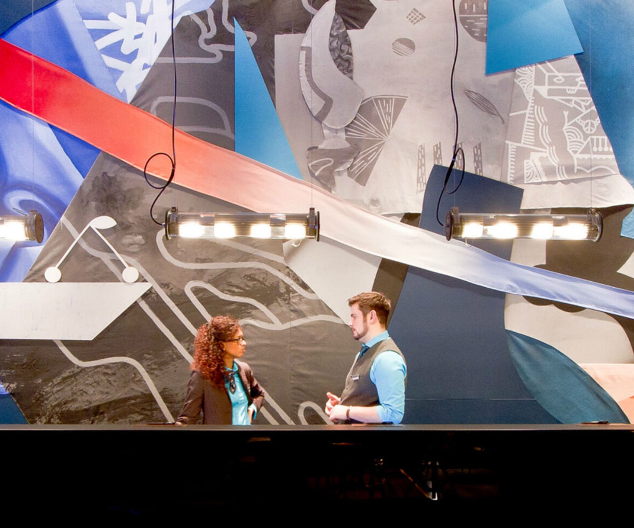 Hotel Berlin Alexanderplatz Motel One große Rezeption mit zwei Mitarbeitenden, die miteinander sprechen