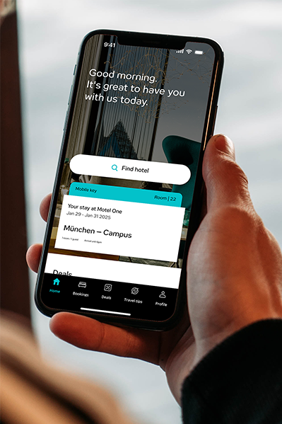 Hand hält Smartphone mit geöffneter Hotel-App, die Begrüßung, Buchungsdetails und Suchfunktion für Hotels anzeigt.