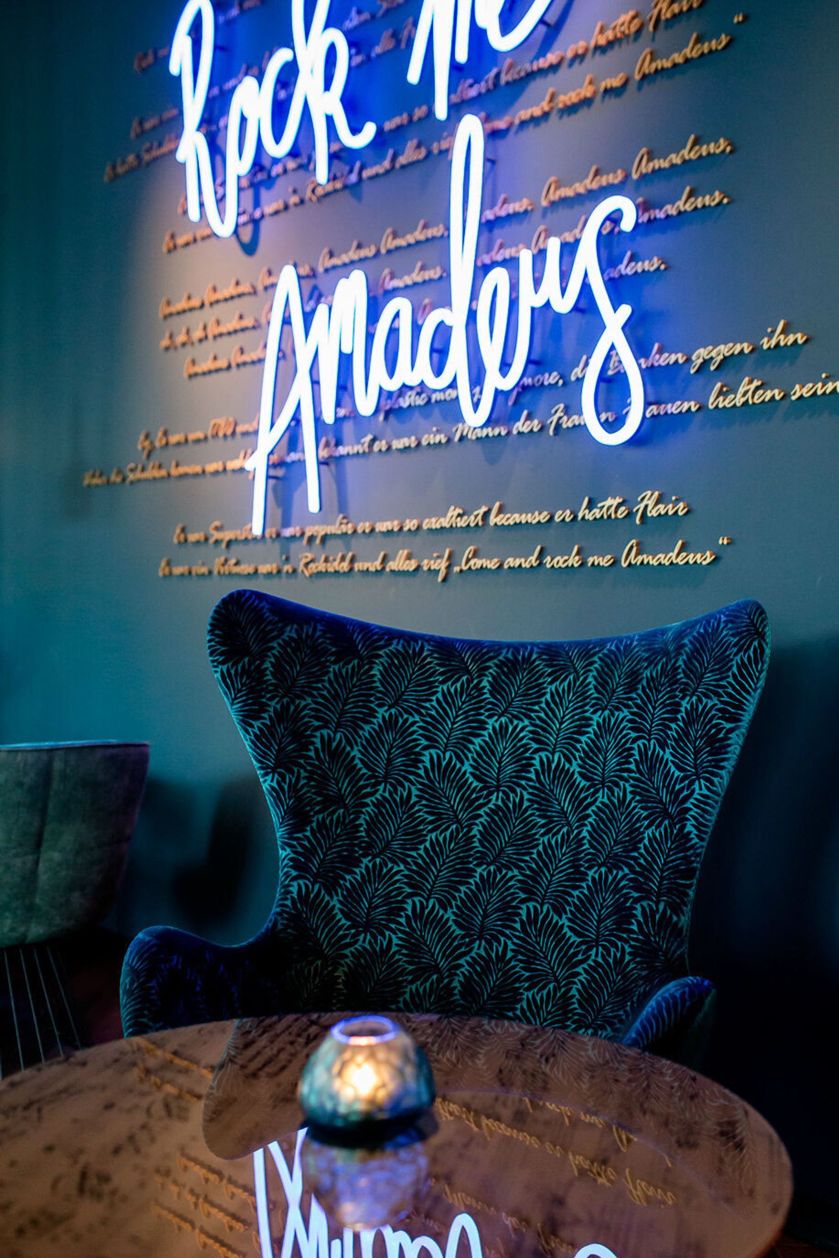 Hotel Salzburg Mirabell Motel One Sessel und leuchtende Neonschrift mit "Rock me Amadeus" an der Wand