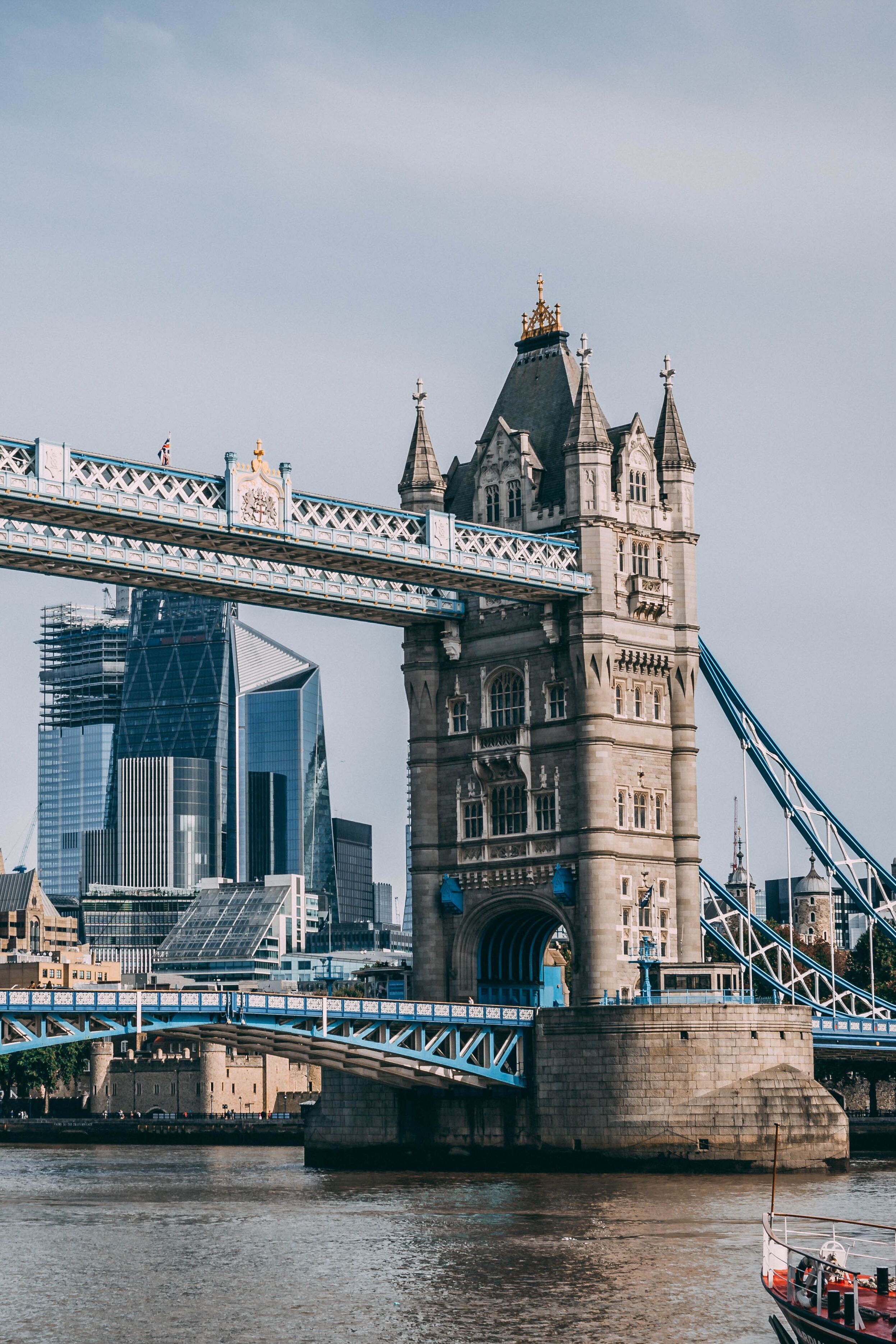 Die Tower Bridge in London mit ihren markanten Türmen überspannt den Fluss Themse, im Hintergrund sind moderne Hochhäuser zu sehen.