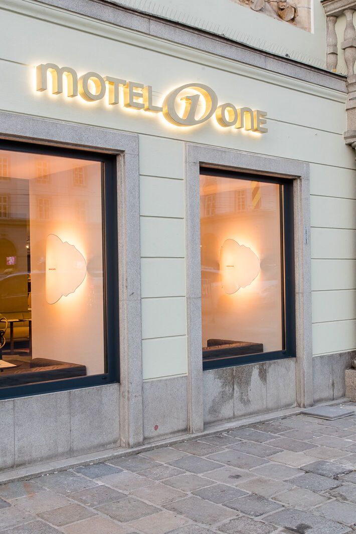 Hotel Linz Hauptplatz Motel One Blick auf den Eingangsbereich mit leuchtendem Logo
