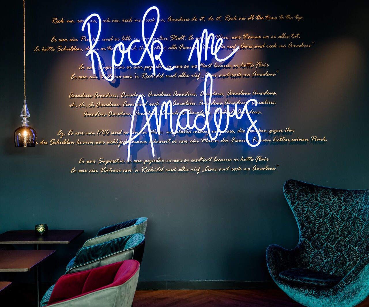 Hotel Salzburg Mirabell Motel One Lounge mit Egg Chair und Leuchtschrift "Rock me Amadeus" an der Wand
