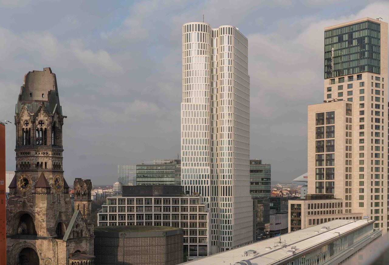 Blick auf die Berliner Skyline mit dem Hochhaus „Upper West“ und der historischen, teilweise zerstörten Kaiser-Wilhelm-Gedächtniskirche im Vordergrund. Die Stadt kombiniert Architekturgeschichte mit zeitgenössischem Design.